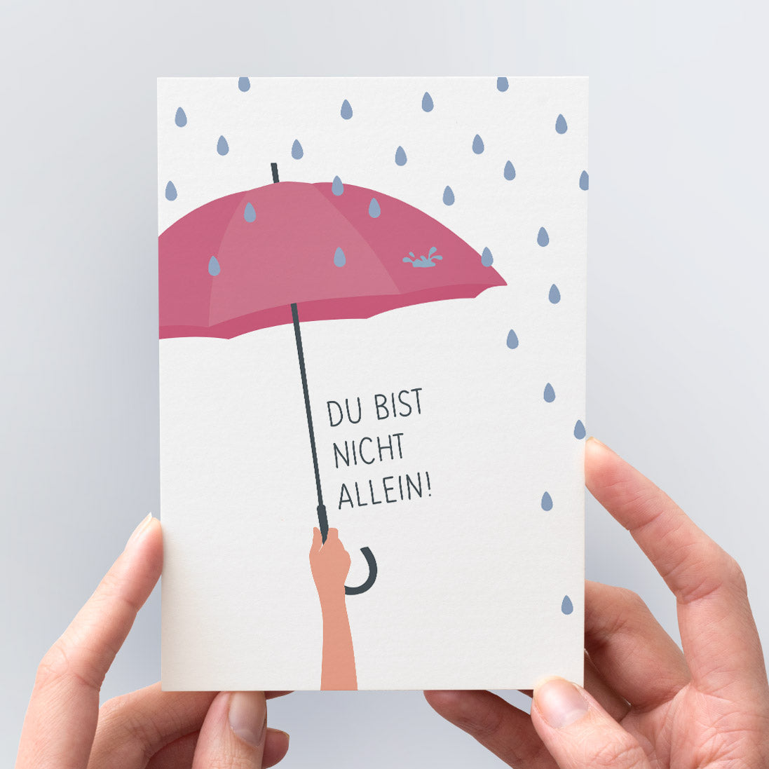 Trost-Postkarte "Du bist nicht allein" - Die Illustration zeigt eine Hand, die einen schützenden Regenschirm hält.
