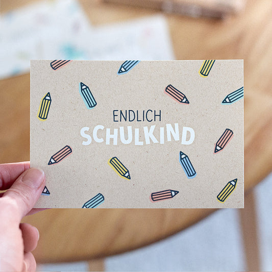 Fröhliche Postkarte für die Einschulung mit dem Aufdruck: „Endlich Schulkind“
