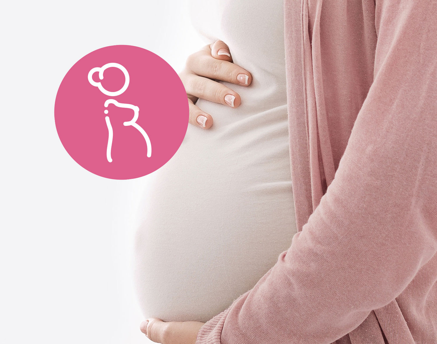 Eine Schwangere hält in entspannter Pose mit beiden Händen ihren Babybauch. Sie trägt eine rosa Strickjacke.