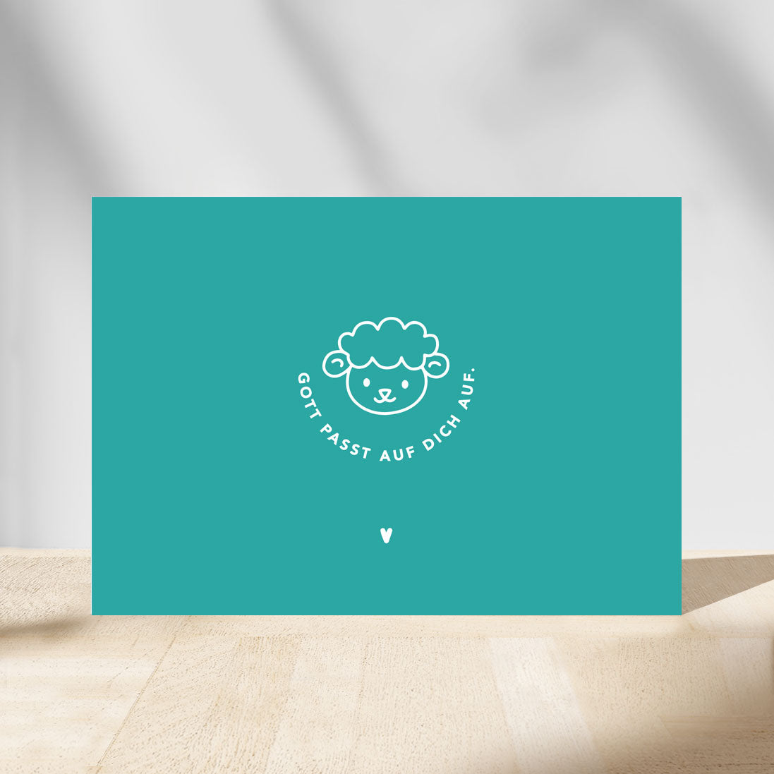 Christliche Postkarte „Gott passt auf dich auf." in Türkis mit weißem Schaf-Illustration und Herzchen – aus dem Postkartenset „Gott hat dich wow gemacht." der himmlisch-Kollektion von herzseiten.com.