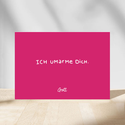Christliche Postkarte „Ich umarme dich. Gott." in knalligem Pink mit weißer Handschrift-Typografie – aus dem Postkartenset „Gott hat dich wow gemacht." der himmlisch-Kollektion von herzseiten.com.